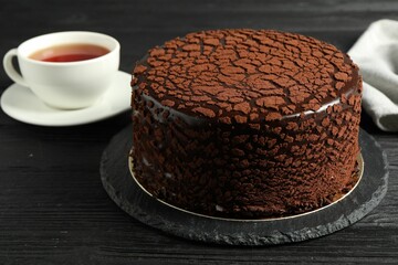 Delicious chocolate truffle cake and tea on black wooden table