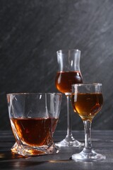 Different delicious liqueurs in glasses on black wooden table