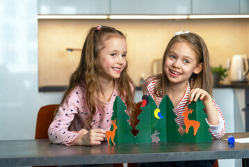 Happy girls funny make craft from colored paper and laugh. Children cut and glue animals in summer...