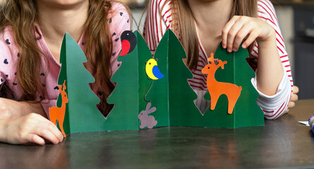 Close up of childrens hands make diy from colored paper. Girls with handmade craft. Leisure,...