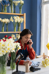 Business and floristry concept. happy smiling florist woman taking order on cellphone working at...