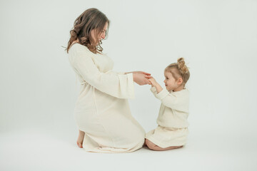 Beautiful young pregnant woman with her little 3 yearold daughter on white background. Stylish...
