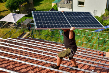 Dachdecker beim Aufbau einer Photovoltaikanlage auf einem neu gedeckten Ziegeldach: Das...