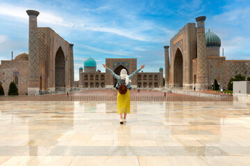 Uzbekistan, Samarcanda - young girl standing with open arms looking Registan square