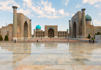 Awesome view of the Registan Square in Samarkand, Uzbekistan. The Ulugh Beg Madrasah and the Sher-Dor Madrasah reflected in wet floor. The Registan is a popular tourist attraction of Central Asia.