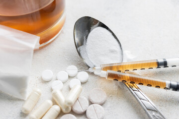 Narcotic substances in spoon, dope powder in transparent plastic bag, syringes with drugs dose, white pills and glass of alcohol drink on textured background. Concept of addiction and bad habits