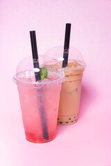 Two plastic glasses with bubble tea and ice in female hands. Trendy summer drink