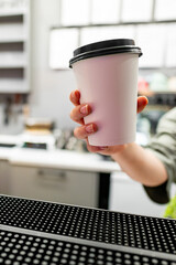 Hand holding a white coffee cup in a modern kitchen, symbolizing comfort and the start of a new day