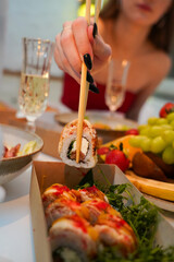 Sushi, friends and restaurant cheers with champagne for birthday celebration or social event. Celebrate toast, happy and smile of women with japanese food eating and drinking together with alcohol