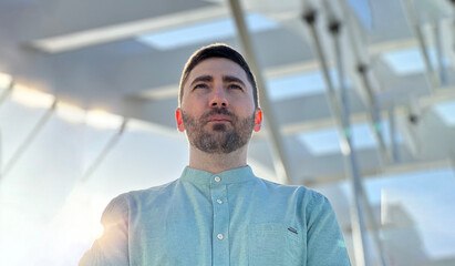 Portrait of a young man standing under big construction looking into distance 