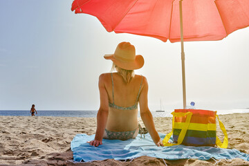 Anonymous woman sitting on blanket on beach