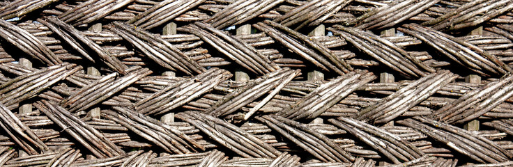 The fence is woven from dry branches, close-up. Weaving from dry willow branches. Wicker willow...