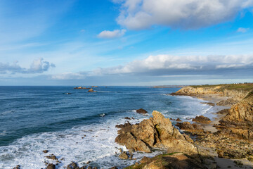 Fototapeta na wymiar Sur la côte sauvage bretonne : eaux turquoises, écume blanche, falaises imposantes, rochers immergés, nature préservée.