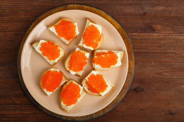 Sandwich with red caviar on a plate on a wooden table