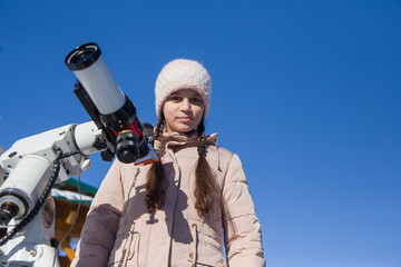 A girl stands next to a solar telescope.