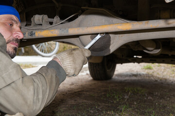 A man is servicing the rear axle of an off-road vehicle.