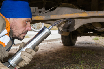 A man pours transmission oil into the rear axle of an off-road vehicle.