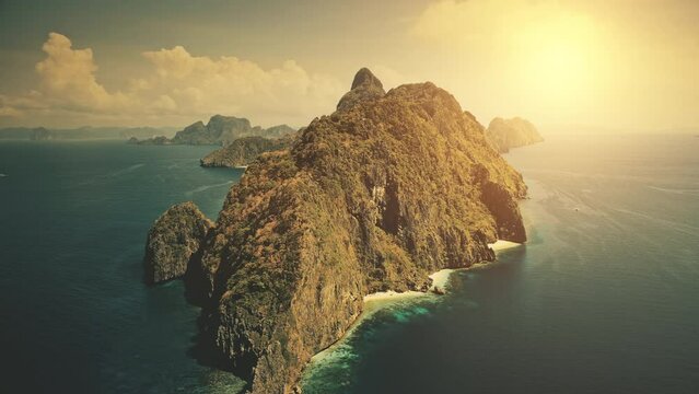 Sunset at tropical island at blue ocean bay. Sun shine aerial view. Nobody wild nature scenery at amazing tropic mountains islet of Palawan, El Nido, Philippines archipelago. Cinematic summer vacation