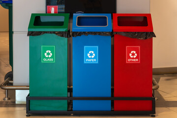 Close-up of green, blue, and red trash cans for separate dumping of glass, paper, and other trash...