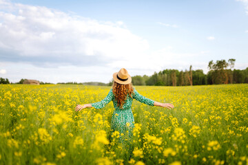 Beautiful woman in bright dress in rapeseed field. Nature, vacation, relax and lifestyle. Summer...