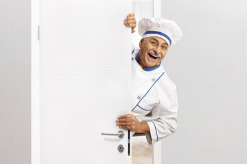 Mature male chef in a uniform opening a door