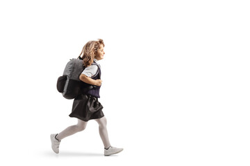 Full length profile shot of a schoolgirl in a uniform carrying a backpack and running