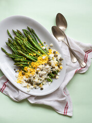 Asparagus salad Mimosa. Spring and Easter salad with grated egg, capers and aromatic dressing. Mint background. Healthy vegetarian balanced recipes for spring, seasonal cuisine