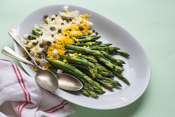Asparagus salad Mimosa. Spring and Easter salad with grated egg, capers and aromatic dressing. Mint background. Healthy vegetarian balanced recipes for spring, seasonal cuisine, front view