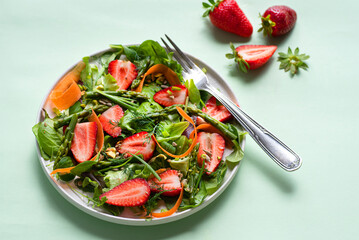 Spring light salad with strawberries, asparagus, carrots, arugula leaves, spinach and flax seeds, nuts and olive oil dressing. Light salads with fruits and berries, sweet and salty taste, dietary bala