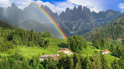 Stunning Alpine scenery of breathtaking Dolomites rocks mountains with rainbow in Italian Alps, South Tyrol Alto adige , Italy. view of Val di Funes and village Santa Maddalena .