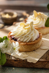 Obraz na płótnie Canvas Sweet cream tarts on rustic wooden board in spring white flowers