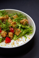 White bowl with lettuce, tomatoes, and chicken salad