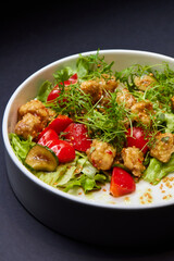 White bowl with lettuce, tomatoes, and chicken salad