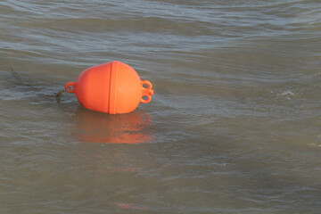 A photo of an orange plastic bouy floating in the sea