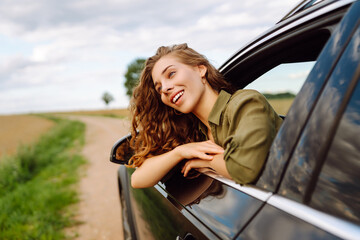 Happy woman on summer road trip travel vacation leaning out car window. Summer trip. Nature,...