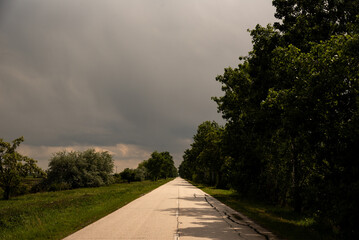 Fototapeta na wymiar Road to the storm, empty road, rainy day, emptiness