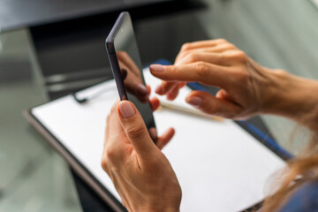 Close up shot of the woman with beautiful hands sitting in the meeting room during business meeting, using her phone. Business