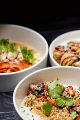 Close up of three bowls with fish ball, leaf vegetable, and plate on table