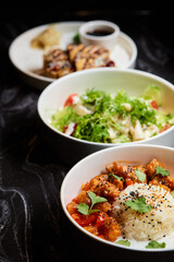 Close up of three bowls with fish ball, leaf vegetable, and plate on table