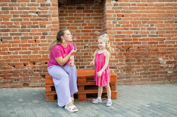 Deaf child with cochlear implant for hearing audio and aid for impairment having fun and laughs with mother outdoor in summer. Sound fitting device to help with communication listening and interaction