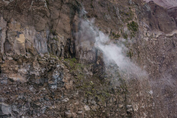 Landscape on top of the crater of dormant Vesuvius volcano with smoke rising out of the rocks,...