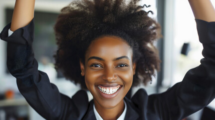 Happy black skinned young African American businesswoman, smiling, hands up in the air. Worker or employee success celebration, office job victory and achievement, excited staff