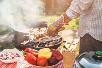 Close up of a male preparing barbecue in backyard. Unknown person roasting meat and flipping it out...