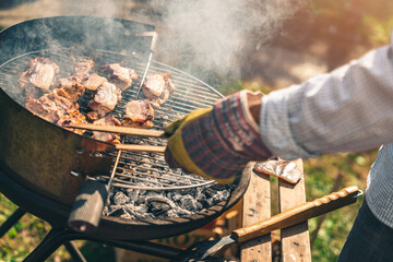 Close up photo of a male preparing barbecue in backyard. Unrecognizable man roasting bacon and...