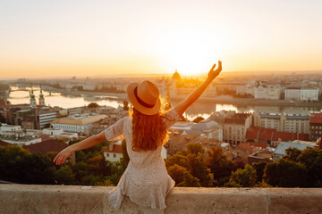 Young girl tourist exploring new city at summer at sunset. Back view. Lifestyle, travel,  nature,...