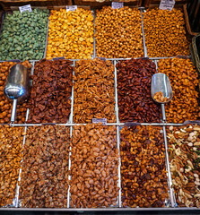 A stall in the famous La Boqueria Market of Barcelona, Spain displays a variety of nuts: plain,...