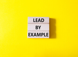 Lead by Example symbol. Concept word Lead by Example on wooden cubes. Beautiful yellow background. Business and Lead by Example concept. Copy space.