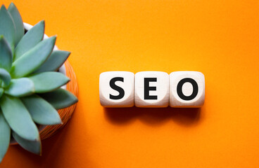 SEO - Search Engine Optimization symbol. Wooden blocks with words SEO. Beautiful orange background...