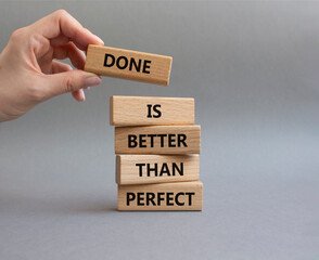 Done is better than Perfect symbol. Wooden blocks with words Done is better than Perfect. Beautiful grey background. Businessman hand. Business concept. Copy space.