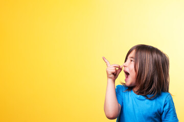Boy with blue t-shirt and long brown hair points with his finger to the empty space in the image